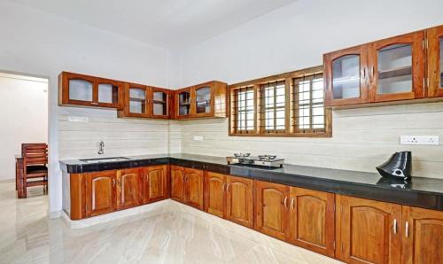 a kitchen with wooden cabinets and a black counter top at PALM GROVE By D2V in Cochin