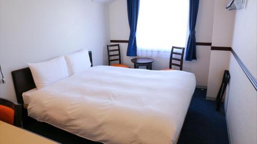 a bedroom with a white bed and a window at Toyoko Inn Shin-osaka Higashi-mikuni Ekimae in Osaka