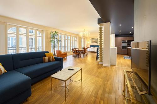 een woonkamer met een blauwe bank en een tafel bij Loft me - Entre art deco et loft à l'americaine in Périgueux