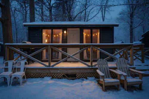 a cabin in the snow with two chairs and a table at Studio Cottage #9 - Virginia Pine in Gravenhurst