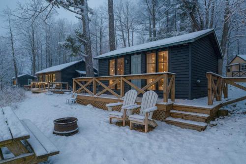 a cabin in the snow with two chairs in front of it at Studio Cottage #9 - Virginia Pine in Gravenhurst