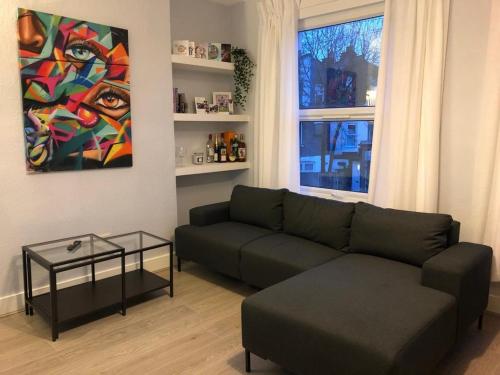 a living room with a green couch and a painting at 1 bedroom flat 15 minutes from Oxford Circus in London
