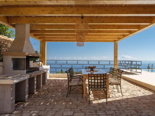 Un patio con mesa y sillas y una estufa. en Armos Stone Villa - Private Pool & Sea Views, by ZanteWize, en Skinária