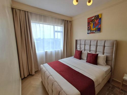 a bedroom with a bed with red pillows and a window at Comfy Bnb in Syokimau