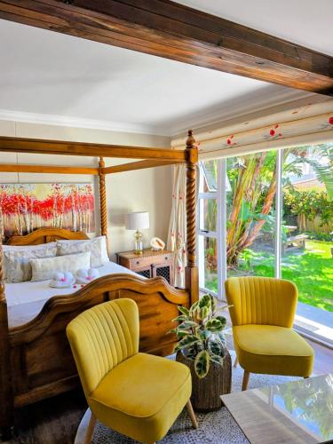 a bedroom with a wooden bed and two chairs at Hermanus Manor in Hermanus