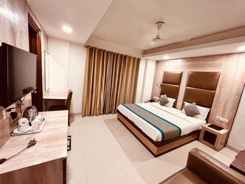 Hotel Ganga Ashoka- 100m from Ganga Ghat في ريشيكيش: غرفة فندقية مع سرير وتلفزيون بشاشة مسطحة