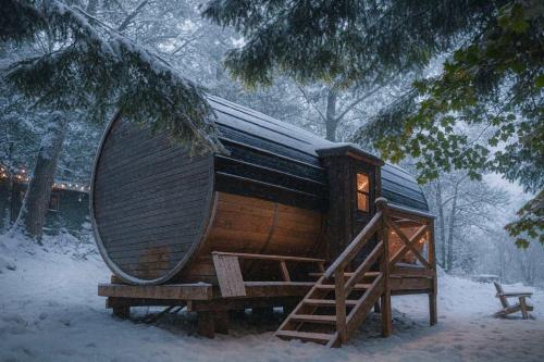 Una gran cabaña de madera en la nieve con una escalera. en Lakefront Barrel in Parry Sound #16, en Parry Sound