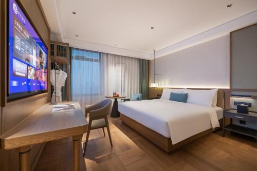 ein Hotelzimmer mit Bett und Flachbildfernseher in der Unterkunft Manxin Hotel Wuhan Jianghan Road Pedestrian Street in Wuhan