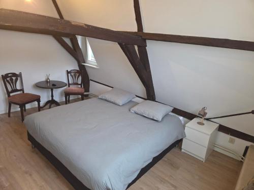 a bedroom with a bed with two chairs and a table at Slapen bij De Buren in Alkmaar