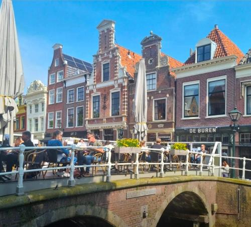 a bridge over a canal with people sitting at tables at Slapen bij De Buren in Alkmaar