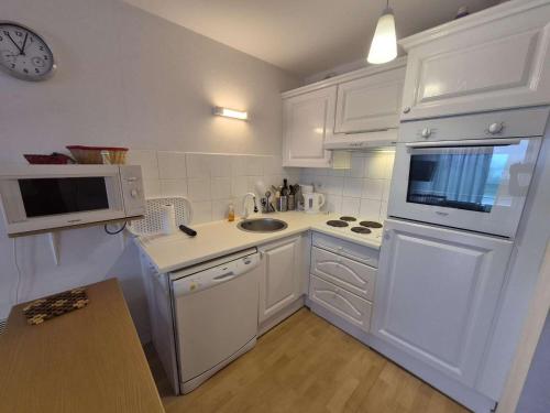 a white kitchen with a sink and a microwave at Confortable appartement 4 personnes avec balcon, parking à Stella Plage - FR-1-236-173 in Stella-Plage
