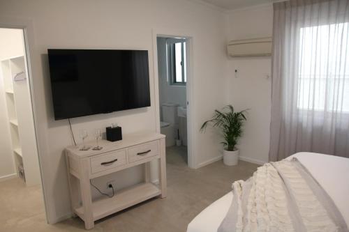 a white bedroom with a television on a dresser at The Esperance Accommodation in Esperance