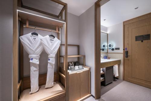 ein Badezimmer mit weißen Hemden, die auf einem Kleiderständer hängen in der Unterkunft Manxin Hotel Wuhan Jianghan Road Pedestrian Street in Wuhan