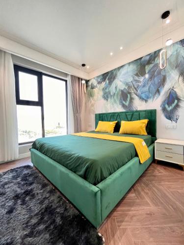 a bedroom with a green bed with a painting on the wall at Quy Nhon Alt cosy apartment in Quy Nhon