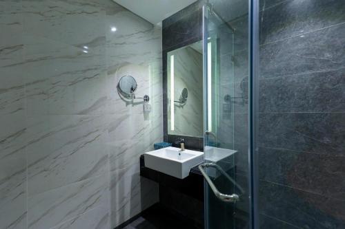 a bathroom with a sink and a shower with a mirror at Quy Nhon Alt cosy apartment in Quy Nhon