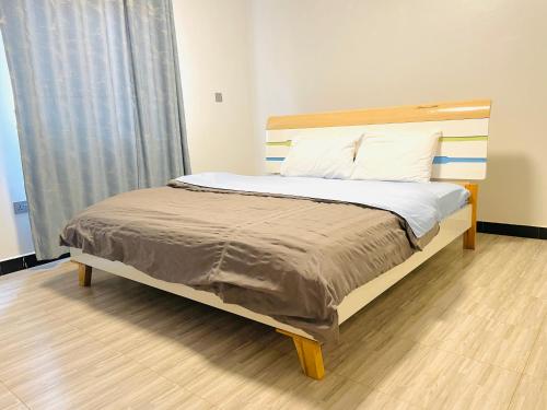 a bed with a wooden headboard in a room at Zuri stays in Kampala