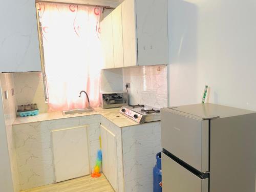 Elle comprend une petite cuisine avec des placards blancs et un réfrigérateur. dans l'établissement Zuri stays, à Kampala