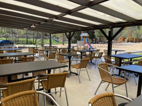 un patio esterno con tavoli, sedie e parco giochi di Le Hameau de l'Ourthe Houffalize a Houffalize