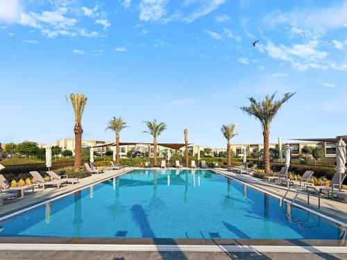 a large swimming pool with chairs and palm trees at Golden Stays - Luxe 4BR Villa Family-Friendly and Fully Equipped in Dubai
