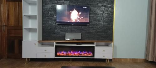 a living room with a tv and a fireplace at Happy Home House in Ruhengeri