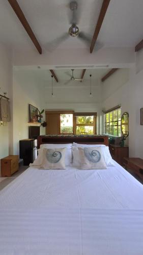 a large white bed in a room with windows at Casa Munti Garden Lodge in Daet