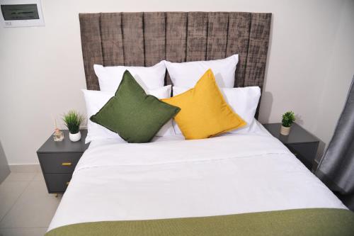 a bed with yellow and green pillows on it at Sentlhaga 1 Bed Self Catering Apartment, Sarona City,Habitat Kappa, Gaborone in Gaborone