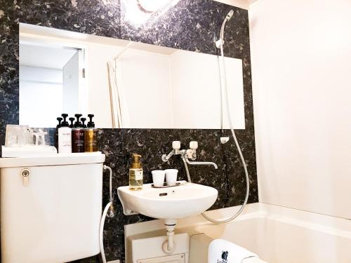 a bathroom with a sink and a mirror at HOTEL LiVEMAX BUDGET Iyo Mishima in Shikokuchuo