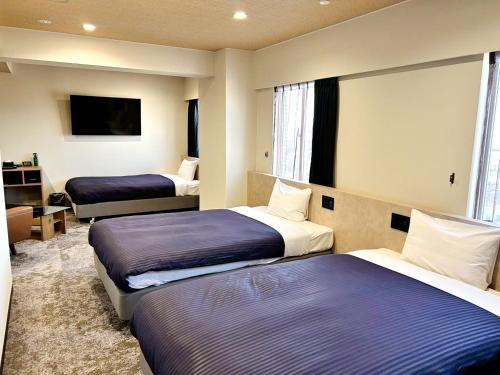 a hotel room with two beds and a tv at HOTEL LiVEMAX BUDGET Iyo Mishima in Shikokuchuo
