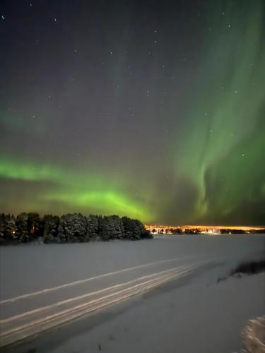 an aurora in the sky over a snow covered field at Northern Lights River Nest in Rovaniemi