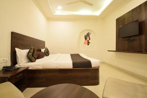 a hotel room with a bed and a tv at Hotel Krishna Palace in Udaipur