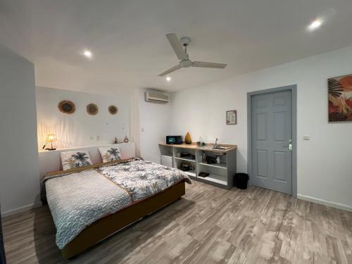 Bungalow Terra - Sarramea في Sarraméa: غرفة نوم مع سرير ومكتب ومروحة سقف