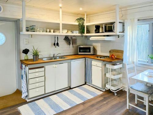 Cottage By The Sea On Djurö في Djurhamn: مطبخ بخزائن بيضاء ومغسلة
