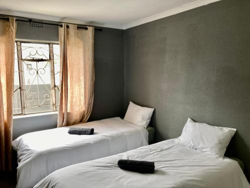 Unit 1, TraversHub Sleeps 6 Self-Catering Group Belhar, CT في Belhar: سريرين في غرفة بها نافذة