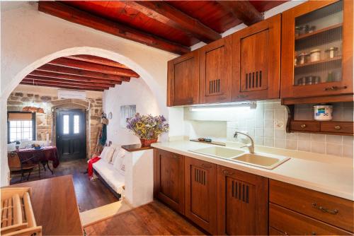 a kitchen with wooden cabinets and a living room at Spitaki traditional house in Vóroi