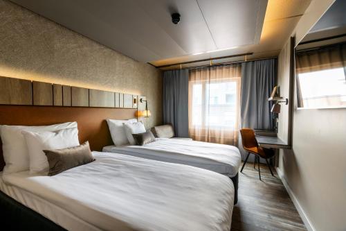 a hotel room with two beds and a window at Original Sokos Hotel Vaakuna Hämeenlinna in Hämeenlinna