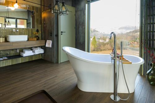 Dom w trawach في اوسترزوكي دولن: حوض استحمام في حمام به نافذة كبيرة