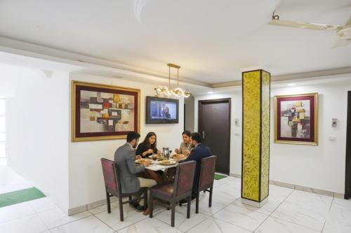 FabHotel Limewood في دهرادون: مجموعة من الناس يجلسون حول طاولة في مطعم