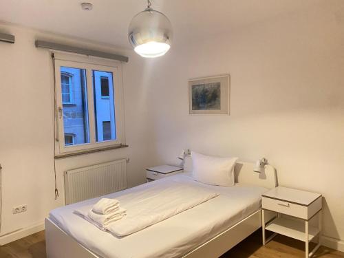 a white bedroom with a bed and a window at Apartment an der Dürerstraße in Nuremberg