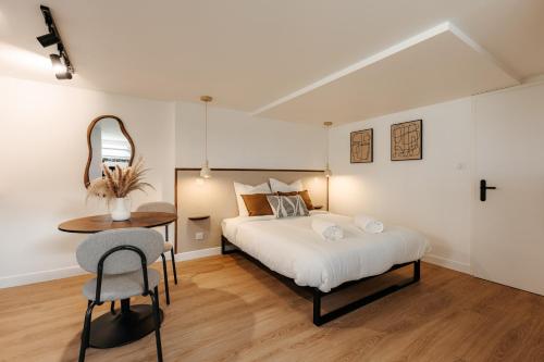 a bedroom with a bed and a table and a chair at L'Alma- Accès Privée-Proche Aéroport-Parking-Wifi in Achenheim