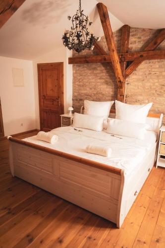 a large white bed in a room with wooden floors at Privates Ferienhaus mit großem Garten in Rauen