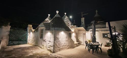a white building with a table and chairs at night at Il trullo della nonna in Martina Franca