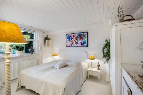 a white bedroom with a bed and two windows at Tina Risager bed & breakfast in Sindal