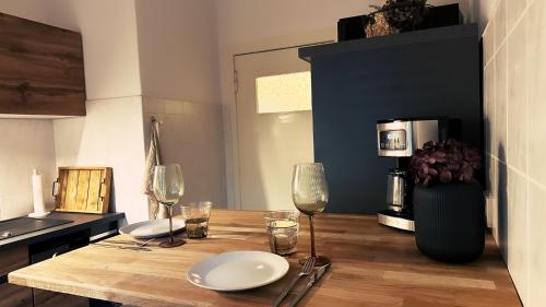 - une table en bois avec des verres et des assiettes dans la cuisine dans l'établissement Ferienwohnung Seelenruh, à Falkensee