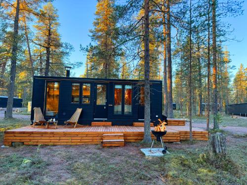 a black tiny house in the woods with a fireplace at Lapland Landscape Cabin with Nature View, Sauna, Fireplace & Kitchen, Ylläs, Äkäslompolo, Borealis Village in Äkäslompolo