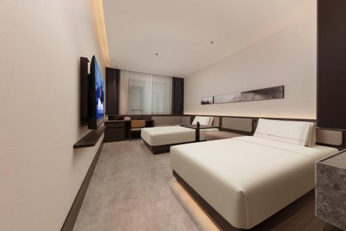 Atour Hotel Shanghai North Bund Riverside International Plaza في شانغهاي: غرفة فندقية تحتوي على سريرين وأريكة