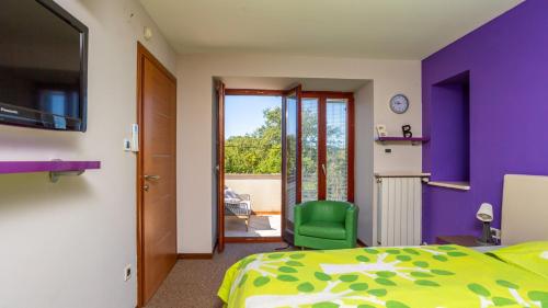 Beautiful Villa Grande with pool Island Krk في Gostinjac: غرفة نوم بجدران أرجوانية وسرير وكرسي أخضر