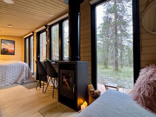 a room with a fireplace and a bedroom with a bed at Lapland Landscape Cabin with Nature View, Sauna, Fireplace & Kitchen, Ylläs, Äkäslompolo, Borealis Village in Äkäslompolo