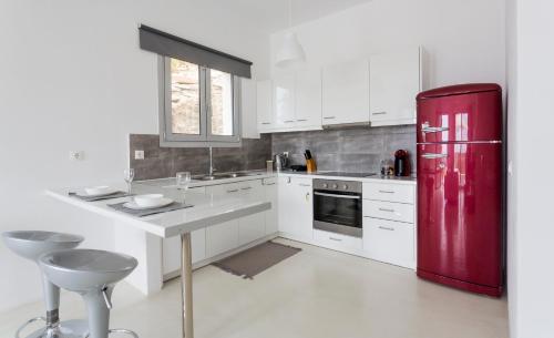 a kitchen with a red refrigerator and white cabinets at Kea Villa Thea- Villa Ilios in Vourkarion