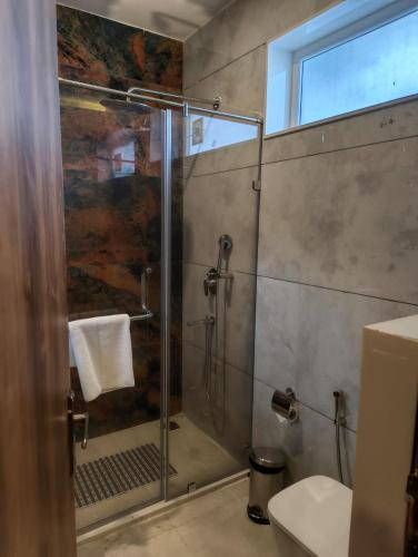 a bathroom with a shower with a glass door at Amritara Chakra River Resort - Closest Luxury Resort to Neelkanth Temple in Mohan Chatti