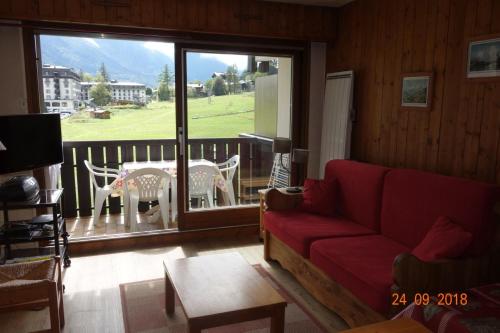a living room with a red couch and a balcony at Appartement Les Balcons du Savoy in Chamonix-Mont-Blanc